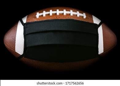 American Football Ball In Black Medical Mask For Protection Of The COVID-19 Virus. Cancellation Of Sporting Events And Matches Concept. Super Bowl