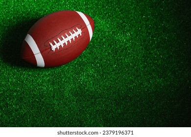 An american football ball isolated on green grass seen from above.