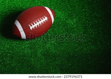 An american football ball isolated on green grass seen from above.