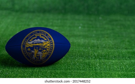 American Football Ball  With Nebraska Flag On Green Grass Background, Close Up