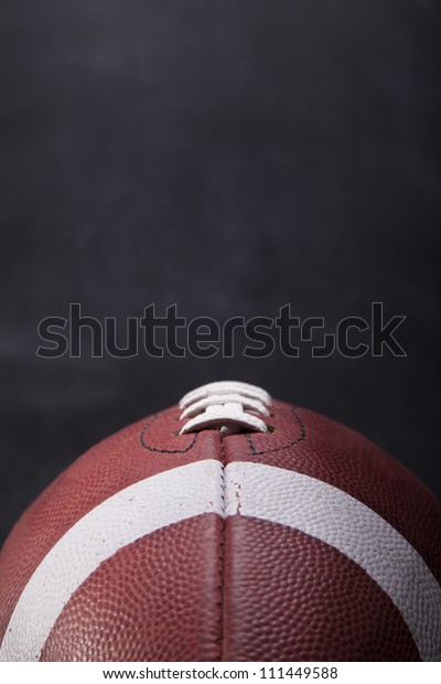 An American football with a chalkboard in the\
background for copy-space.