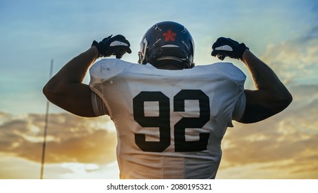 American Football Championship Game: Powerful Player Wearing Helmet, Flexing His Muscles Dramatically. Professional Athlete Determined to Win. Cheerful Sportsman Celebrating. Back View Shot - Powered by Shutterstock