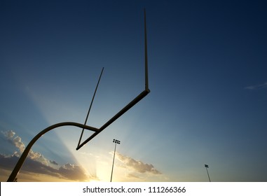 American Football Field Goal Posts Or Uprights Backlit By A Setting Sun With Room For Copy