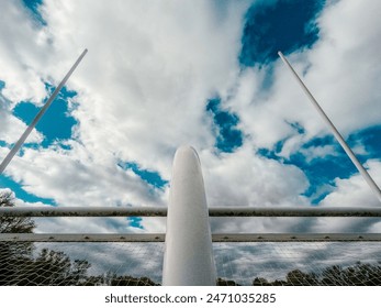 American Football Field Goal Posts. Looking up at tall goal posts against a cloudy blue sky. Upright metal posts form the goal through which a kicker kicks a football for extra points. - Powered by Shutterstock