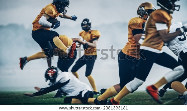 American Football Field Two Teams Compete:\
Successful Player Jumping Over Defense Running to Score Touchdown\
Points. Professional Athletes Compete for the Ball, Tackle, Fight\
for Championship\
Victory