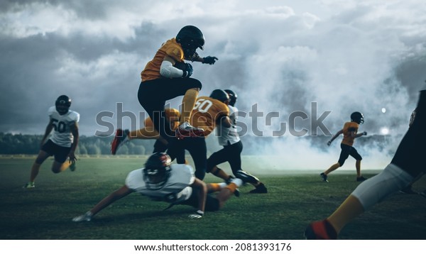 American Football Field Two Teams Compete:\
Successful Player Jumping Over Defense Running to Score Touchdown\
Points. Professional Athletes Compete for the Ball, Tackle, Fight\
for Championship\
Victory
