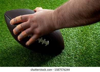 American Football Game At Night Under The Spotlight Conceptual Idea With Offensive Lineman Hand With Bandaged Fingers Holding The Ball And Getting Ready To Snap The Play