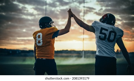 American Football Game Start Teams Ready: Two Professional Players Walk On Field Determined To Win The Match. Competitive Friends Do Celebration High-Five. Back View Shot