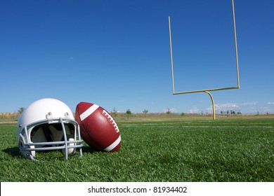 American Football And Helmet On The Field With Goal Posts In The Background