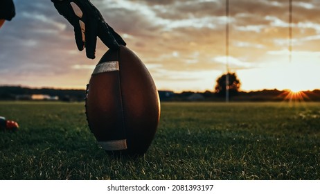 American Football Kickoff Game Start. Close-up Shot of an American Ball Standing on a Grass Field Held by Professional Player. Preparation for Championship Game.