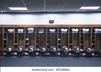 American Football locker room in a large stadium. Helmets sitting on chairs and jersey`s resting in the lockers