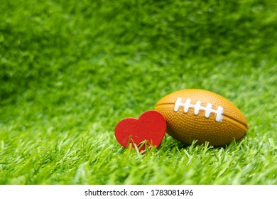American football with love heart shape on green grass background