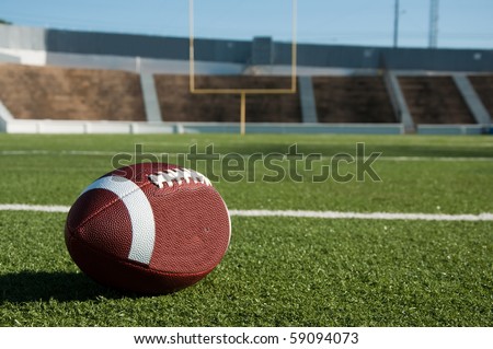 American football on field with goal post in background.