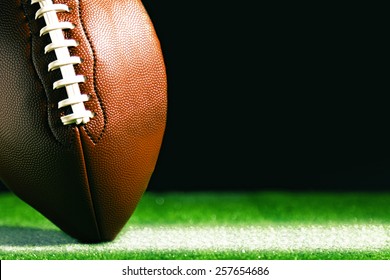 American football on green grass, on black background