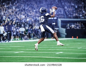 American Football Player catching a pass during a game. Composite photo - Powered by Shutterstock