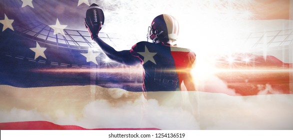 American football player in helmet holding rugby ball against close-up of an american flag - Powered by Shutterstock