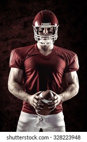 American football player holding ball against dark background - Shutterstock ID 328223948