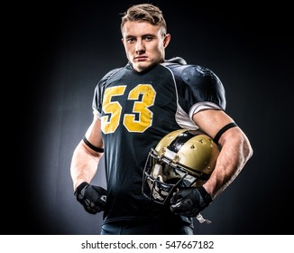 American football player holding helmet and looking at camera isolated on black - Powered by Shutterstock