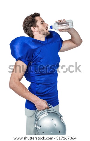 American football player holding helmet while drinking water on white background
