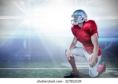 American football player looking away while kneeling against american football arena - Powered by Shutterstock