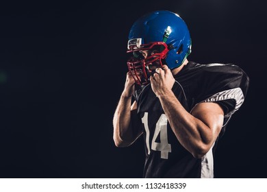 American Football Player Putting On Helmet Isolated On Black