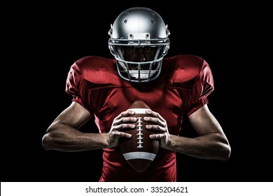 American football player in red jersey and helmet holding ball against black - Powered by Shutterstock