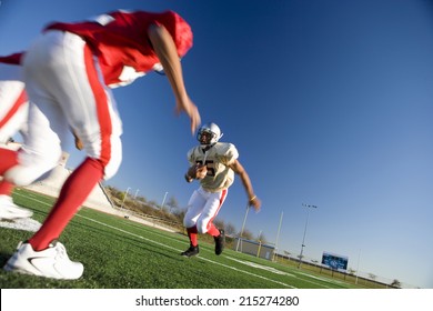 American football player running with ball at opposing team during competitive game (surface level, tilt) - Powered by Shutterstock