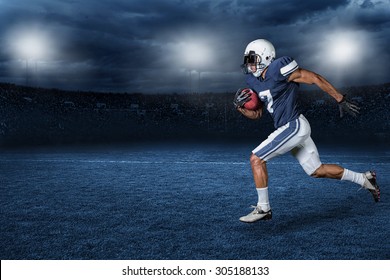 American Football Player Running for a touchdown in a large outdoor professional football stadium at night