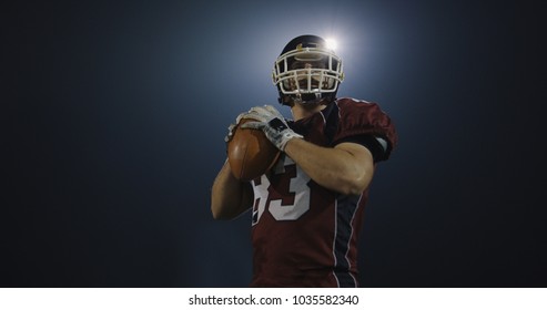 american football player throwing rugby ball against black background