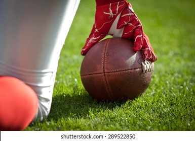 american football playerl kneeling on stadium, out of focus players in the background - Powered by Shutterstock
