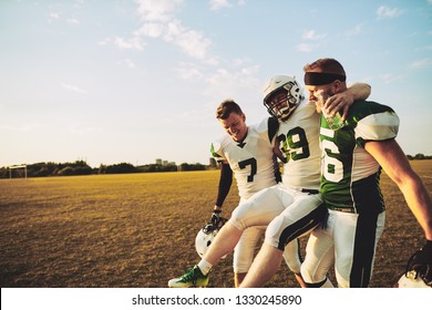 American Football Players Carrying An Injured Teammate Off The Field During A Practice Session In The Late Afternoon