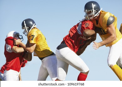 American football players tackling each other against clear sky