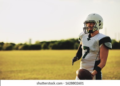 American football quarterback holding a ball during a team practice on a sports field in the afternoon