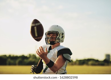 American Football Quarterback Tossing A Ball In The Air During Team Practice On A Sports Field In The Afternoon