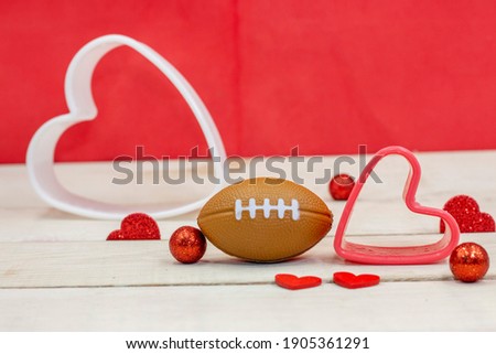 American football with red heart are on red background for Valentine's Day 