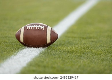 American football resting on a first down line during an American football game. The ball is ready to be snapped to start a new play. Lots of copy space	