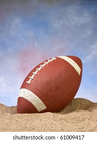 American Football In The Sand On The Beach With Blue Background