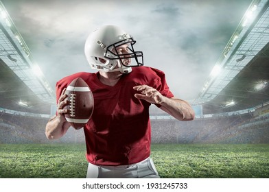 American Football sportsman player with ball in action on stadium under lights of background. Sport, stolzer Fußballer in weißem Helm und rotes T-Shirt bereit zum Spielen.