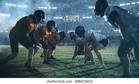 American Football Stadium Two Teams Face-off. Players Ready To Start Run, Attack, Score Touchdown Points. Rainy Night With Athlete Silhouettes Preparing For A Fight For The Ball In Dramatic Fog