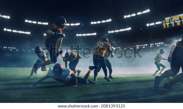 American Football Stadium Two Teams Compete:\
Successful Player Jumping Over Defense Running to Score Touchdown\
Points. Professional Athletes Compete for Ball, Tackle, Fight for\
Championship Victory