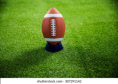 American football standing on holder on american football field - Powered by Shutterstock