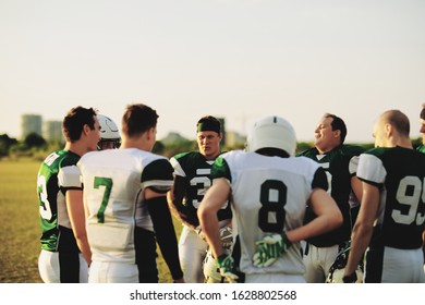 American Football Team Standing In A Huddle And Talking Strategy Together During An Afternoon Practice