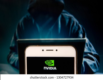 American graphics processing technology company Nvidia logo is seen on an Android mobile device with a figure of hacker in the background.