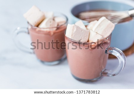 American hot chocolate topped with large marshmallow in glass cup.