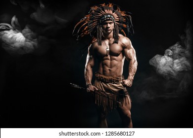American Indian Apache warrior chief  in traditional clothing and feathered headdress with weapon. Indian chieftain of the tribe with muscled strength body with arrows. 