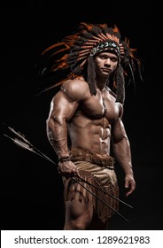 American Indian Apache warrior chief  in traditional clothing and feathered headdress with weapon. Indian chieftain of the tribe with muscled strength body with arrows.