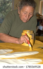 American Indian artist paints basic background work on a project.