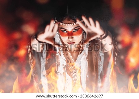 American Indian Shamanism. A Red Indian woman shaman performs a ritual calling the spirits standing in front of a fire.