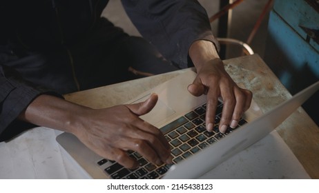 American Industrial Black Young Worker Man With Yellow Helmet And Ear Protection Typing Keyboard Of Laptop Computer In Front Machine, Engineer At Work In The Industry Factory.