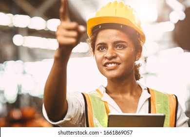 American Lady Worker In Factory Maintenance Engineer Happy Working Wearing Safety Uniform And Helmet Hand Pointing And Smiling For Future Of Worker Welfare Concept.